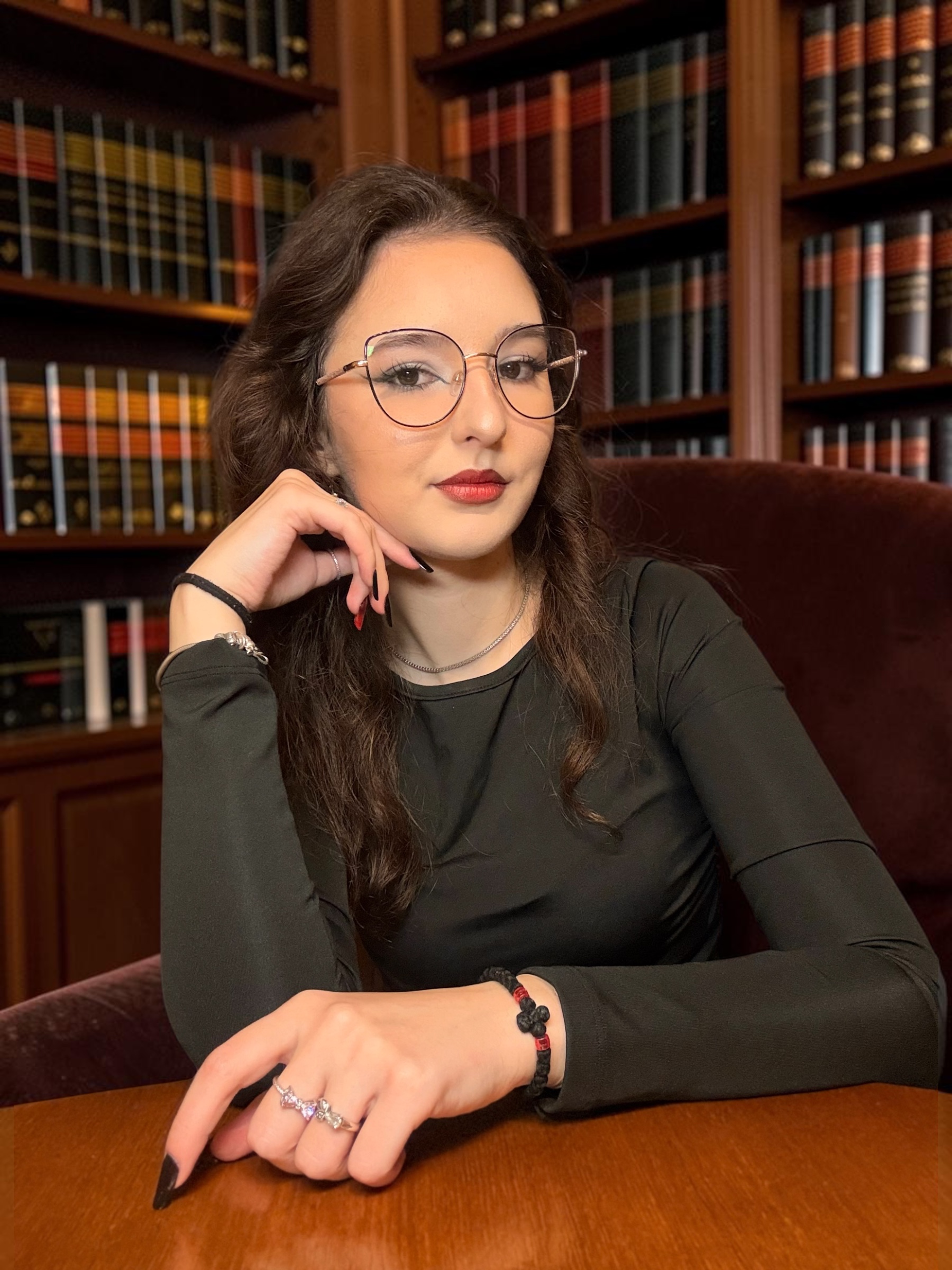 Maria-Teofana in black, looking at the camera with her hand beside her face